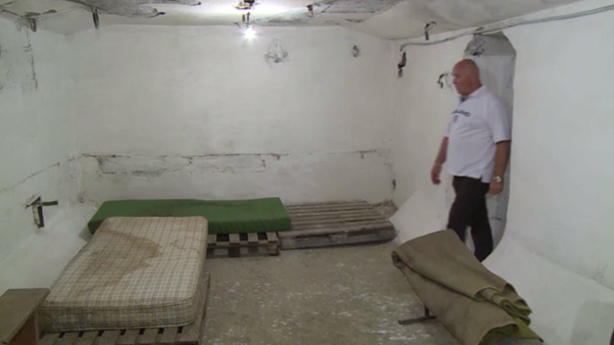 Vitaly Dubinin, local resident walks in the bomb shelter in Lugansk, eastern Ukraine (screenshot from RT video)
