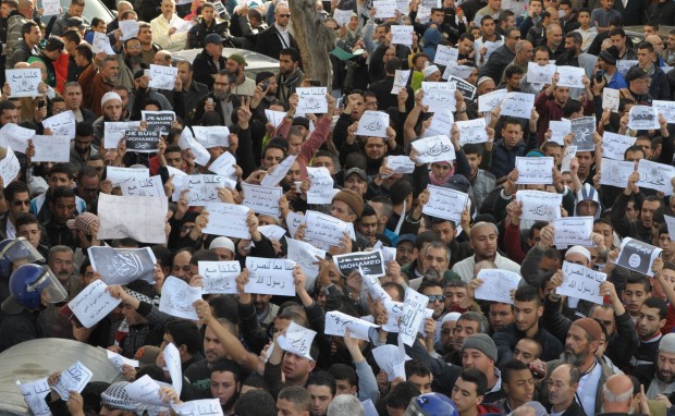Demonstrators hold up signs during a protest in Algiers, Algeria, Friday, Jan. 16, 2015. Algerian police are struggling to contain more than a thousand protesters thronging the streets of the capital denouncing cartoons of the Prophet Muhammad published by French satirical weekly Charlie Hebdo. Chanting "I am not Charlie, I am Muhammad," protesters left their mosques after Friday prayers and gathered in downtown Algiers' May 1 square where they were met by hundreds of riot police. (AP Photo/Sidali Djarboub)