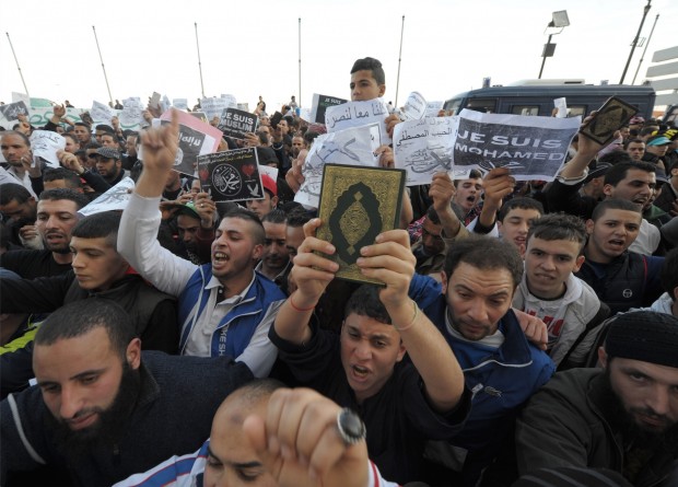 A demonstrator hold up the Quran during a protest against caricatures published in French magazine Charlie Hebdo in Algiers, Algeria, Friday, Jan. 16, 2015. Algerian police are struggling to contain more than a thousand protesters thronging the streets of the capital denouncing cartoons of the Prophet Muhammad published by French satirical weekly Charlie Hebdo. Chanting "I am not Charlie, I am Muhammad," protesters left their mosques after Friday prayers and gathered in downtown Algiers' May 1 square where they were met by hundreds of riot police. (AP Photo/Sidali Djarboub)