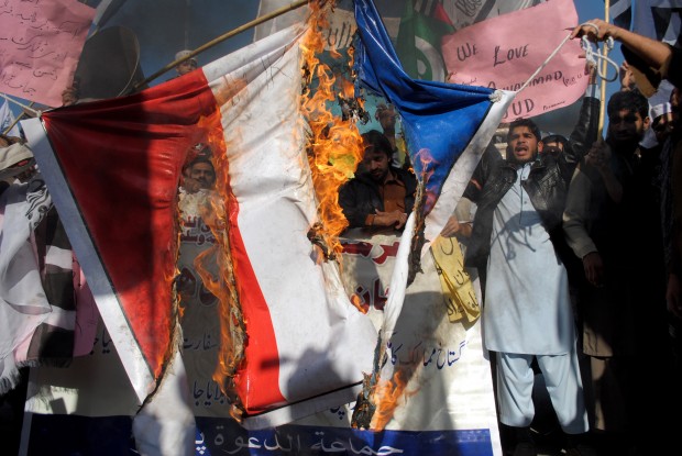 Pakistani protesters burn a representation of a French flag during a protest against  caricatures published in the French magazine Charlie Hebdo, in Peshawar,  Pakistan, Friday, Jan. 16, 2015. Pakistani students are clashing with police during protests against the French satirical magazine that was attacked last week for publishing images of the Prophet Muhammad. (AP Photo/Mohammad Sajjad)