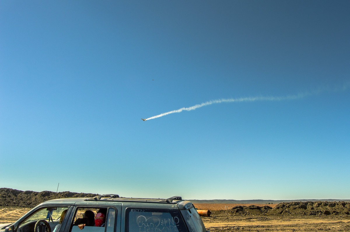 Plane with gas flies over protectors and construction site (Photo: Rob Wilson Photography)