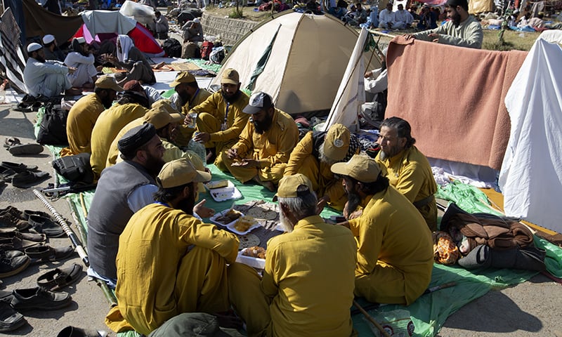 JUI-F supporters have their meal along a roadside during the Azadi March in Islamabad. — AP